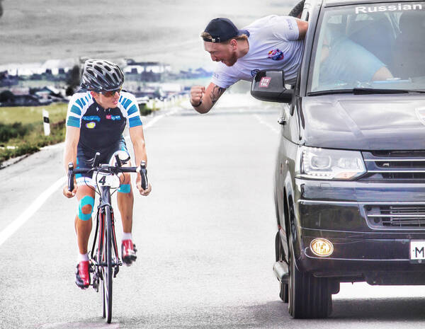Ein Radrennfahrer wird während eines Straßenrennens von einem Mann aus einem russischen Begleitfahrzeug angefeuert.
