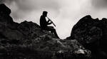 Der kärntner Saxophonist Edgar Unterkirchner sitzt auf der Saualm zwischen Felsblöcken und spielt Sopransaxophon. Seine Silhouette setzt sich deutlich von den Nebelschwaden im Hintergrund ab. Schwarz-Weiß.