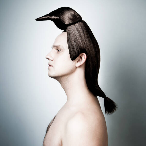 Portrait eines Mannes mit nacktem Oberkörper im Profil. Die langen Haare sind zu einem Pinguin geformt.