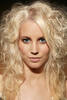 Portrait einer jungen Frau mit Blonden Locken und blauen Augen.