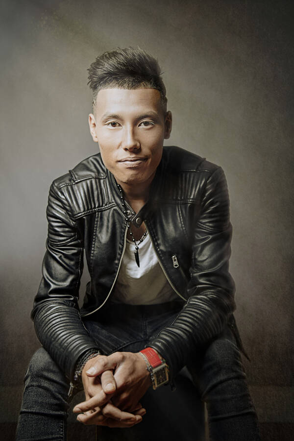 Portrait eines sitzenden jungen Mannes in Lederjacke. Der Mann hat asiatische Züge und einen deutlichen Undercut.