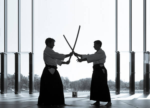 Silhouette zweiter Aikido-Kämpfer mit Holzschwertern. Schwarz-Weiß