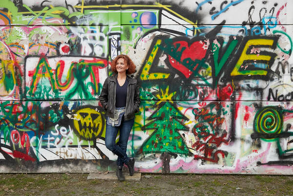 Klaudia Krainer-Aunitz lehnt an einer Wand mit Graffitiy. unter anderem ist das Wort 