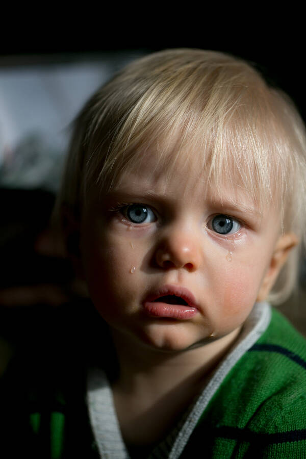 Portrait eines Kleinkindes mit blonden Haaren und blauen Augen.