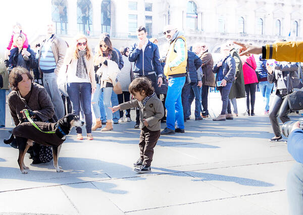 Menschen auf einem Platz: ein Kind zeigt auf einen kleinen Hund.