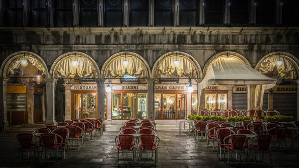 Der menschenleere, nasse, abendliche Außenbereich des Café Quadri in Venedig.
