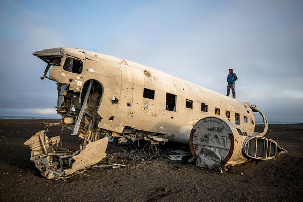 Ein Mann steht auf den Teilen eines Flugzeug-Wracks.
