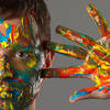 Close-Up-Portrait eines Mannes, dessen Hand und Gesicht in bunten Faben bemalt sind.