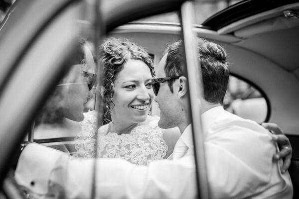 Blick durch das Autofenster auf ein Brautpaar, die im Auto sitzen. Schwarz-Weiß.