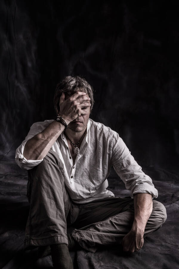 Ein Mann sitzt und hält die Hand vor den Augen.