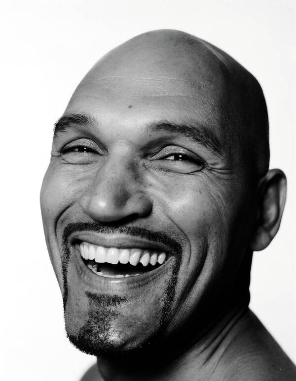 Weitwinkelportrait eines kahlköpfigen, bärtigen Mannes mit einem offenen Lachen. Schwarz-Weiß.