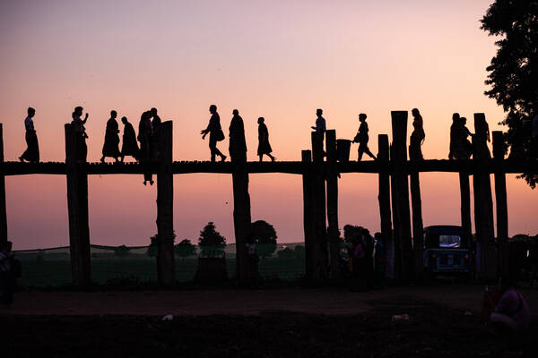 Menschen auf einer Holzbrücke im abendlichen Gegenlicht