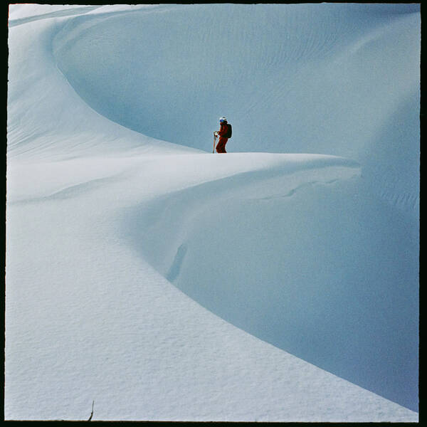 Tourenskifahrer steht an der Kante einer geschwungenen Schneewächte.