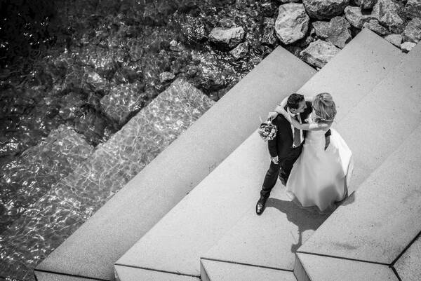 Ein Brautpaar umarmt sich auf einer großen Stiege, die in ein Gewässer führt.