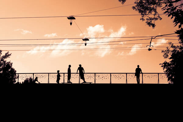 Silhouette von Menschen auf der Grazer Erzherzog-Johann-Brücke. Manche stehen auf Skateboards. Duoton.