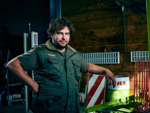 Ein Mann in grüner, kurzärmliger Jacke in einer Werkstatt.