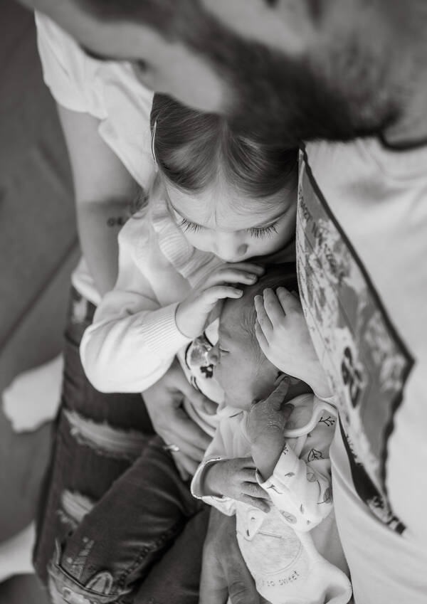 ein Baby wird von der Familie liebevoll gehalten. Schwarz-Weiß.