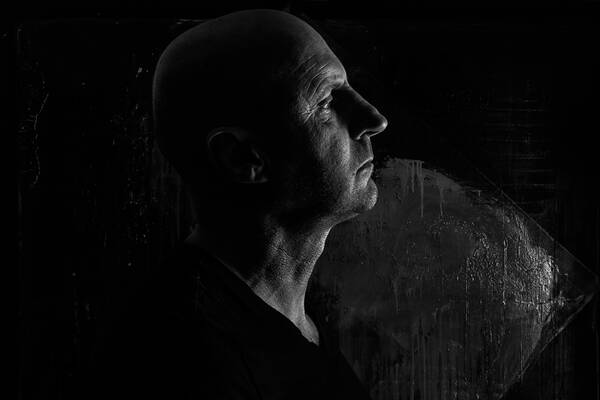 Low-Key-Profil-Portrait eines glatzköpfigen älteren Mannes. Schwarz-Weiß.