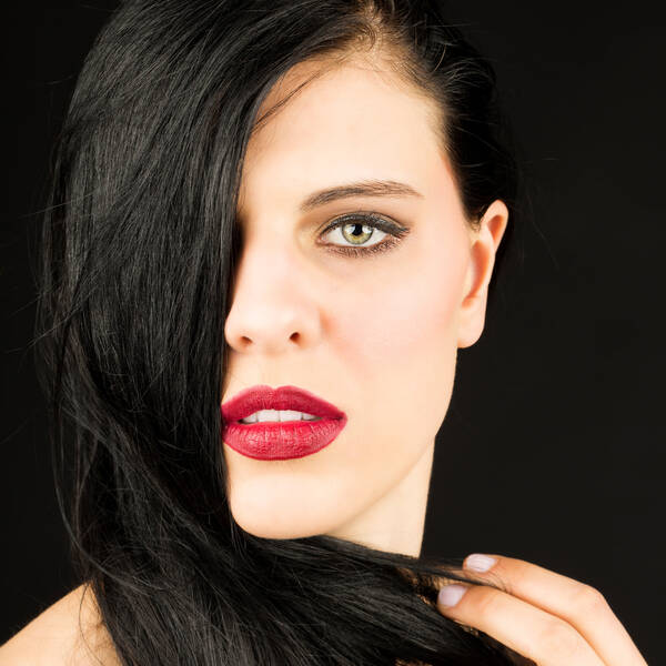 Portrait einer jungen Frau, die nach rechts gekämmten Haare fallen ihr über das rechte Auge.