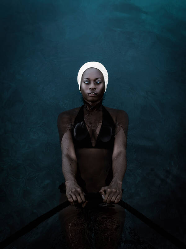 Das Model Jalicia Nightengale im Badeanzug mit Badehaube im Wasser.