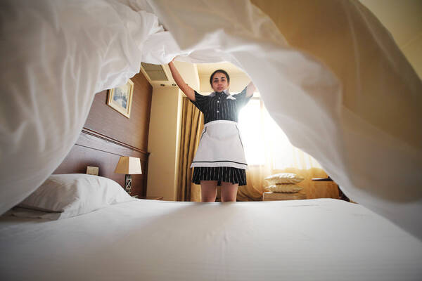 Eine Hotelbedienstete beim Aufbetten.