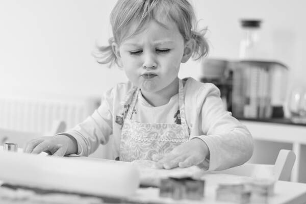 Ein Kind mit Schürze beim Keksebacken. Schwarz-Weiß.