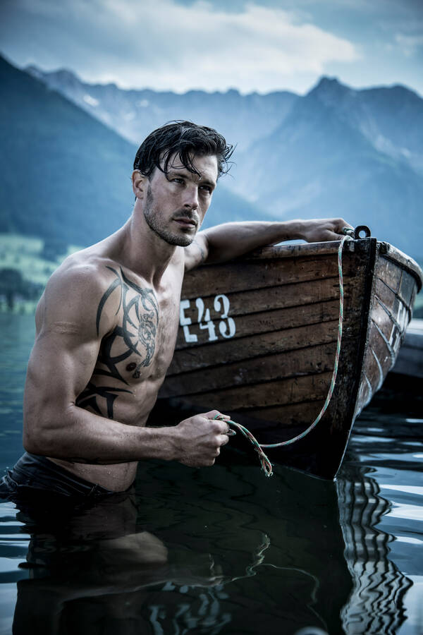 Ein Mann steht im nächtlichen Wasser neben einem Boot.