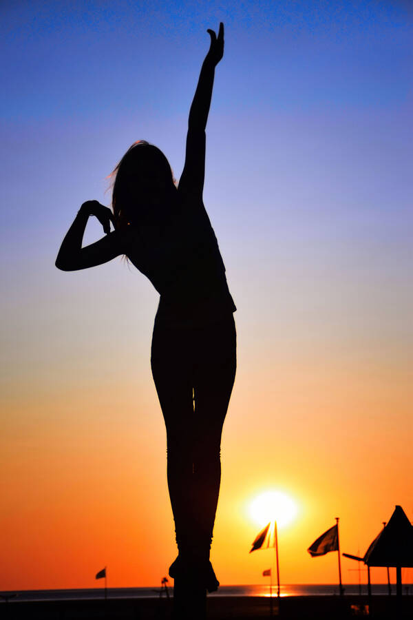Silhouette einer posierenden Frau gegen die tiefstehende Sonne.