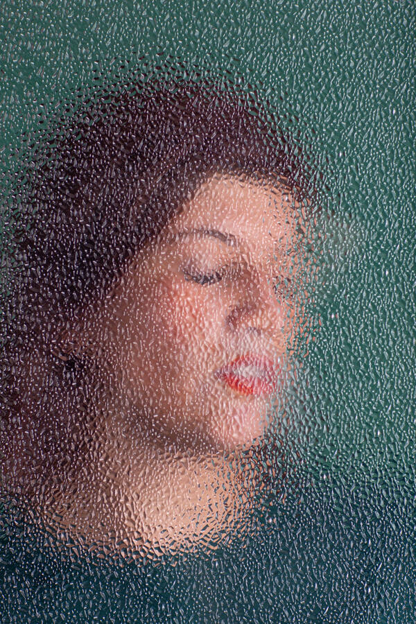 Porrait einer Frau durch eine strukturierete Glasscheibe.