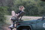Eine blonde Frau sitht anteilslos auf einem Frontsitz eines Safari-Geländewagens.