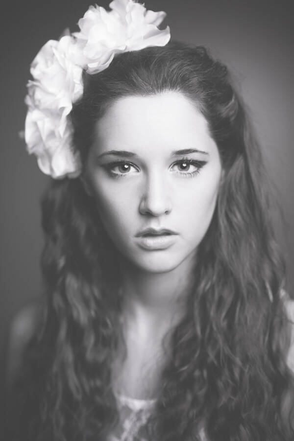 Portrait einer langhaarigen jungen Frau mit weißen Blumen im Haar. Schwarz-Weiß.