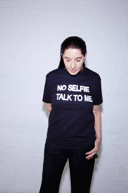 Portrait der Küstlerin Marina Abramovic mit einem T-Shirt mit der Aufschrift: No Selfies - Talk to Me!