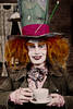 Portrait eines Mannes, der in sseinem Kostüm mit roter wilder Perücke und übergroßem Zilinder sowie einer Teetasse in der Hand an den Mad Hatter (verrückter Hutmacher) aus Alice im Wonderland erinnert.