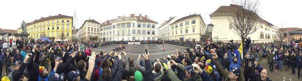 360° Panorama mit vielen Menschen vor gelben Gebäuden.