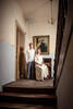 Ein Paar in Hochzeitskleidung in einem Stiegenhaus vor einem alten Gemälde