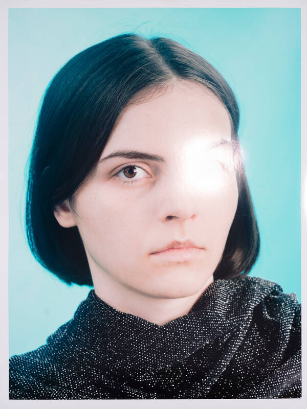 Foto eines Portrait-Fotos einer jungen Frau. Im Bereich des linken Auges reflektiert die glatte Oberfläche der Fotografie eine Lichtquelle.