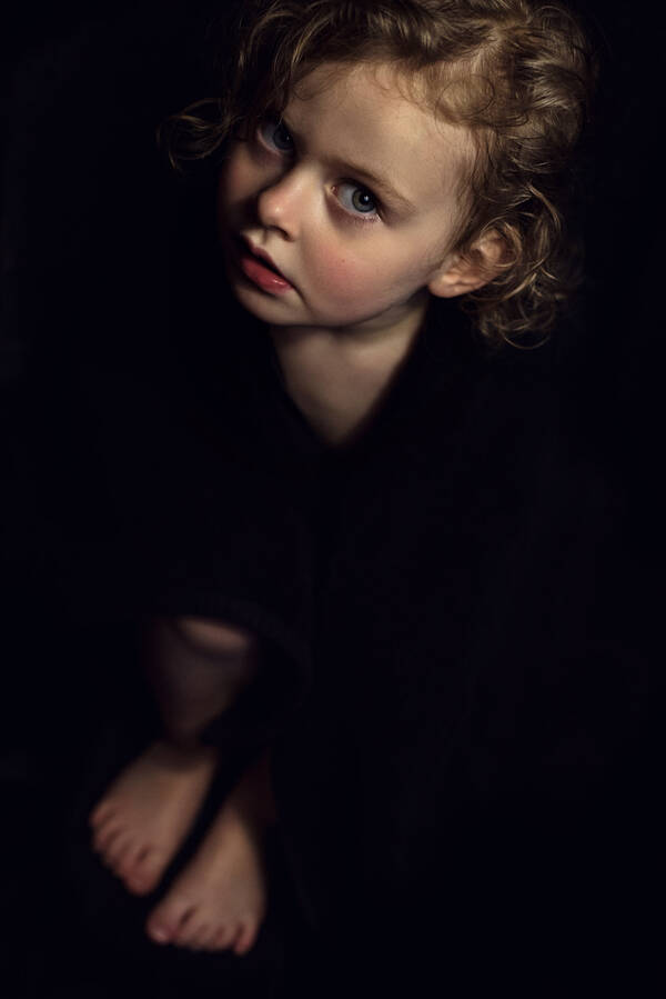 Blick von oben auf ein Mädchen, das fast zur gänze im Dunkeln steht, lediglich das Gesicht und die Füße sind werden beleuchtet.