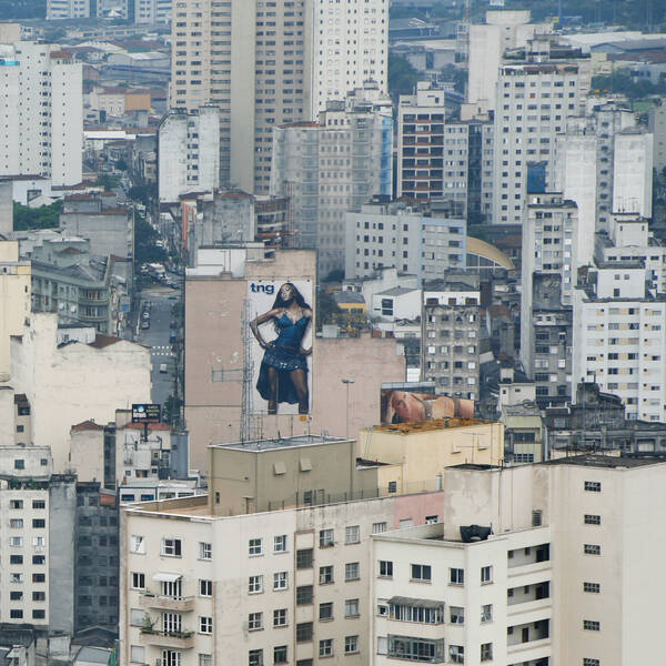 Blick von oben auf alte Wohnblöcke. Auf einem Haus ist ein riesiges Plakat einer Frau.