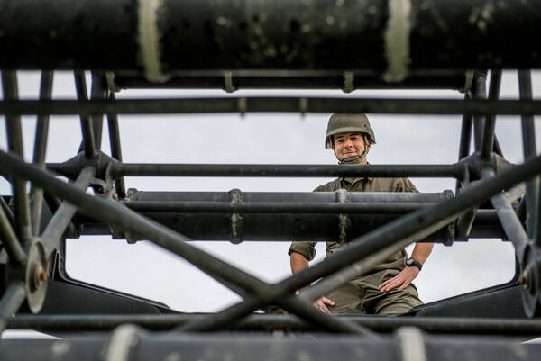 Ein Soldat mit Helm durch ein Militärgrünes Gestänge fotografiert.