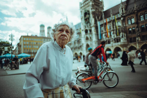Eine alte Frau mit Rollator vor dem Rathaus in München.