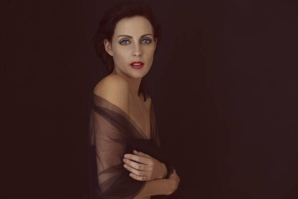Portrait einer Frau mit schwarzem transparentem Schal über der Schulter.