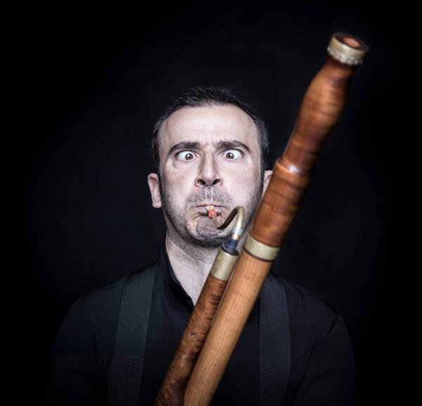 Ein Musiker (Fagott) bläst angestrengt in sein Instrument und verdreht dabei die Augen. 
