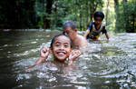 Asiatische Kinder und ein älterer beleibter Mann im Wasser in einem Wald.